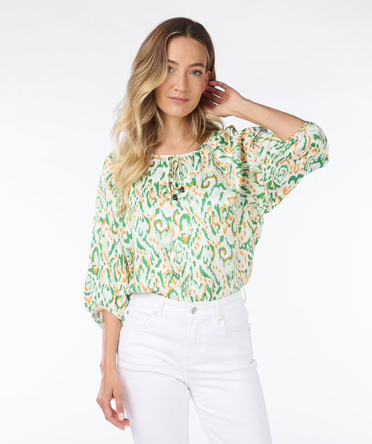 A person wearing an Esqualo Pastel Blouse and white pants stands against a white background, gently touching their hair.