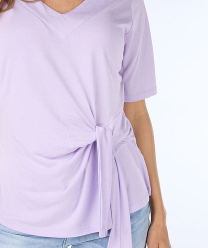 Woman wearing a cute and comfortable Lilac Top by Esqualo with a tie-front detail, paired with light blue jeans made from high-quality materials, posing against a plain white background.