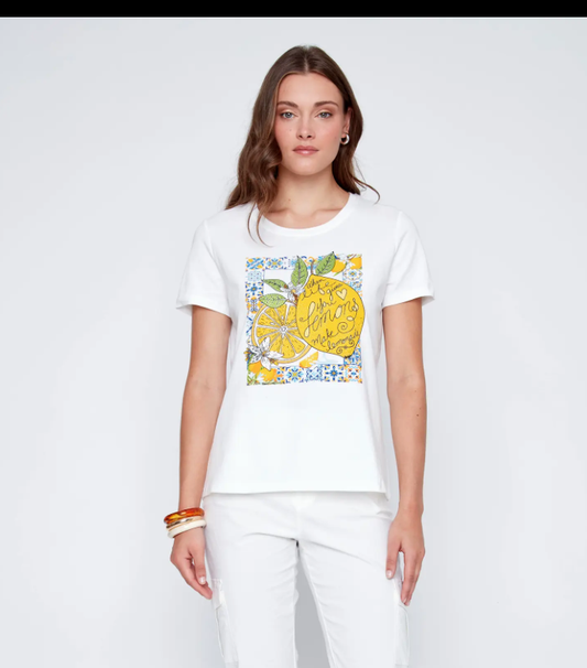 A woman wears a CoCo Y Club short-sleeved T-shirt featuring a colorful lemon print and text, paired with white pants—creating a fresh summer look. The outfit is shown against a plain white background.