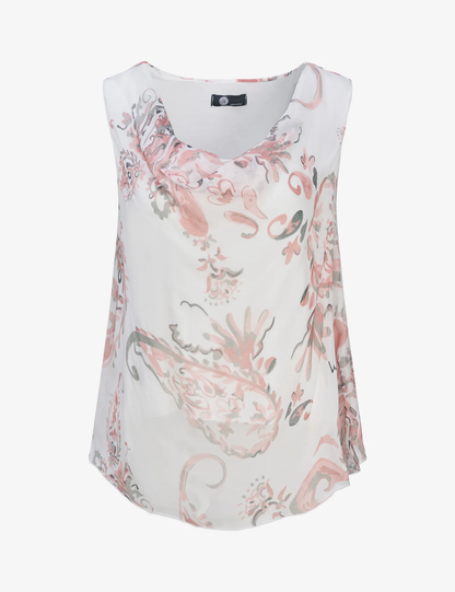 A woman with wavy blonde hair models the M Made In Italy "Made in Italy Woven Top"—a chic paisley print in white, pink, and gray—paired with white pants against a plain light background.