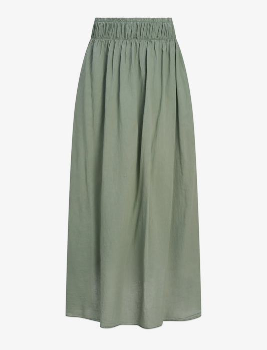 A woman wears the M Made In Italy Woven Maxi Skirt in olive green, featuring an elastic waistband and side pockets, made from breathable fabric, styled with brown flat sandals.