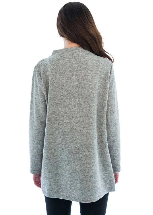 A woman wearing the Trisha Tyler Side Felted Funnel Neck Tunic, designed with multicolored abstract lines on a gray background, stands against a white backdrop, looking down and smiling.