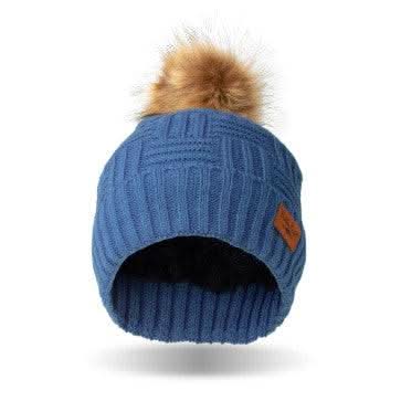 A woman wearing a Britt's Knits Classic Pom Hat in cold weather.