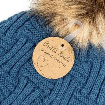 A woman wearing a Britt's Knits Classic Pom Hat in cold weather.