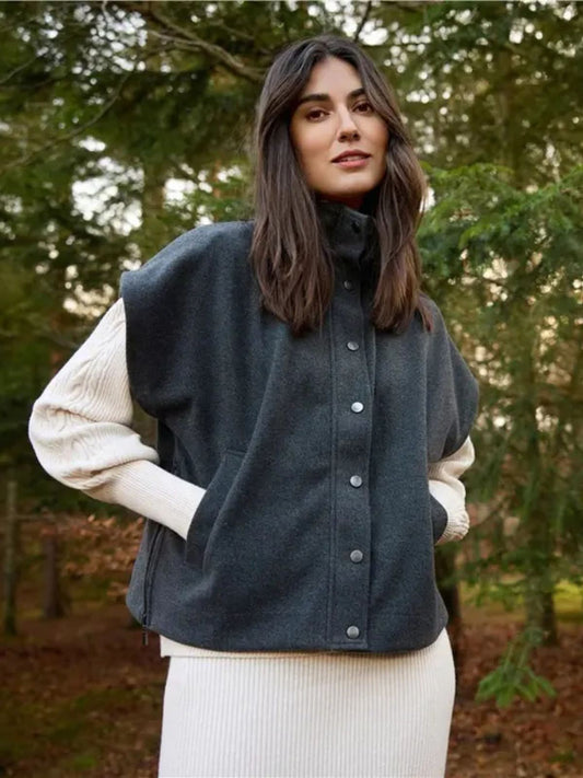 A woman stands outdoors among trees, wearing the Soya Concepts Dark Earth Vest over a cream ribbed long-sleeve dress, highlighting an eco-friendly style.