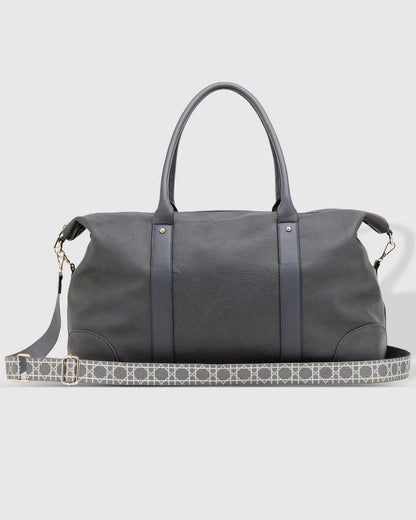 The Alexis Ezra Weekender Travel Bag by Louenhide is a large, dark gray bag made from vegan leather. It features two top handles and an adjustable, patterned shoulder strap.