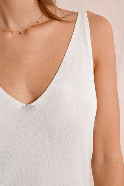 A person smiles in a Kitted Mesh Tank Top by Molly Bracken, paired with a lace skirt, showcasing the versatility of athletic apparel against a plain background.