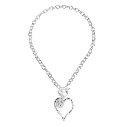 The Merx Silver Heart Pendant features a chain link necklace with a hollow heart charm, toggle clasp, and a small round accent.
