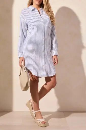 A woman wears the Tribal ROLLED L/S BTN FRT SHIRT DRESS-RIVIERA, pairing it with a beige bag and beige wedge sandals.