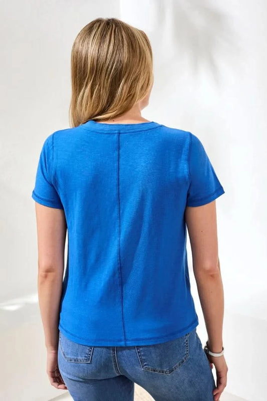 A woman stands indoors wearing the Tribal SLUB KNIT V-NECK TOP with blue cropped jeans and brown sandals—an ideal spring look. A green potted plant is in the background.