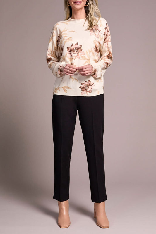 A woman models the Tribal FUNNEL NECK SWEATER with a floral print, paired with black pants and beige heels, posed against a plain neutral background.