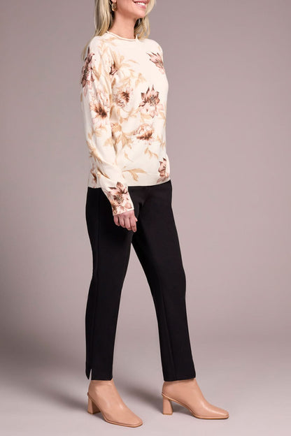 A woman models the Tribal FUNNEL NECK SWEATER with a floral print, paired with black pants and beige heels, posed against a plain neutral background.