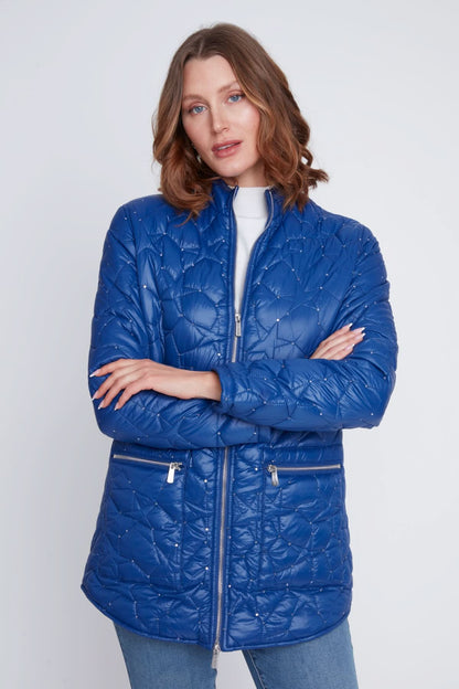 A woman stands with arms crossed, wearing the CoCo Y Club Woven Puff Jacket in blue, featuring zippered pockets, over a white top and blue jeans against a plain light background.