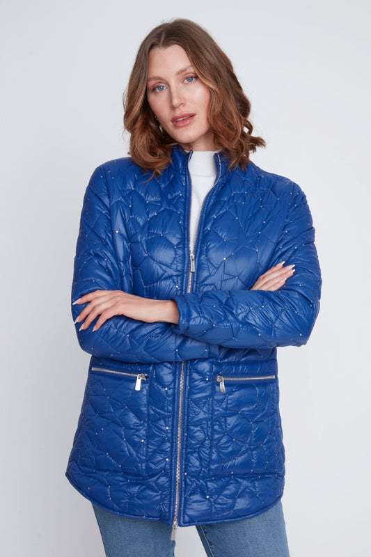A woman stands with arms crossed, wearing the CoCo Y Club Woven Puff Jacket in blue, featuring zippered pockets, over a white top and blue jeans against a plain light background.