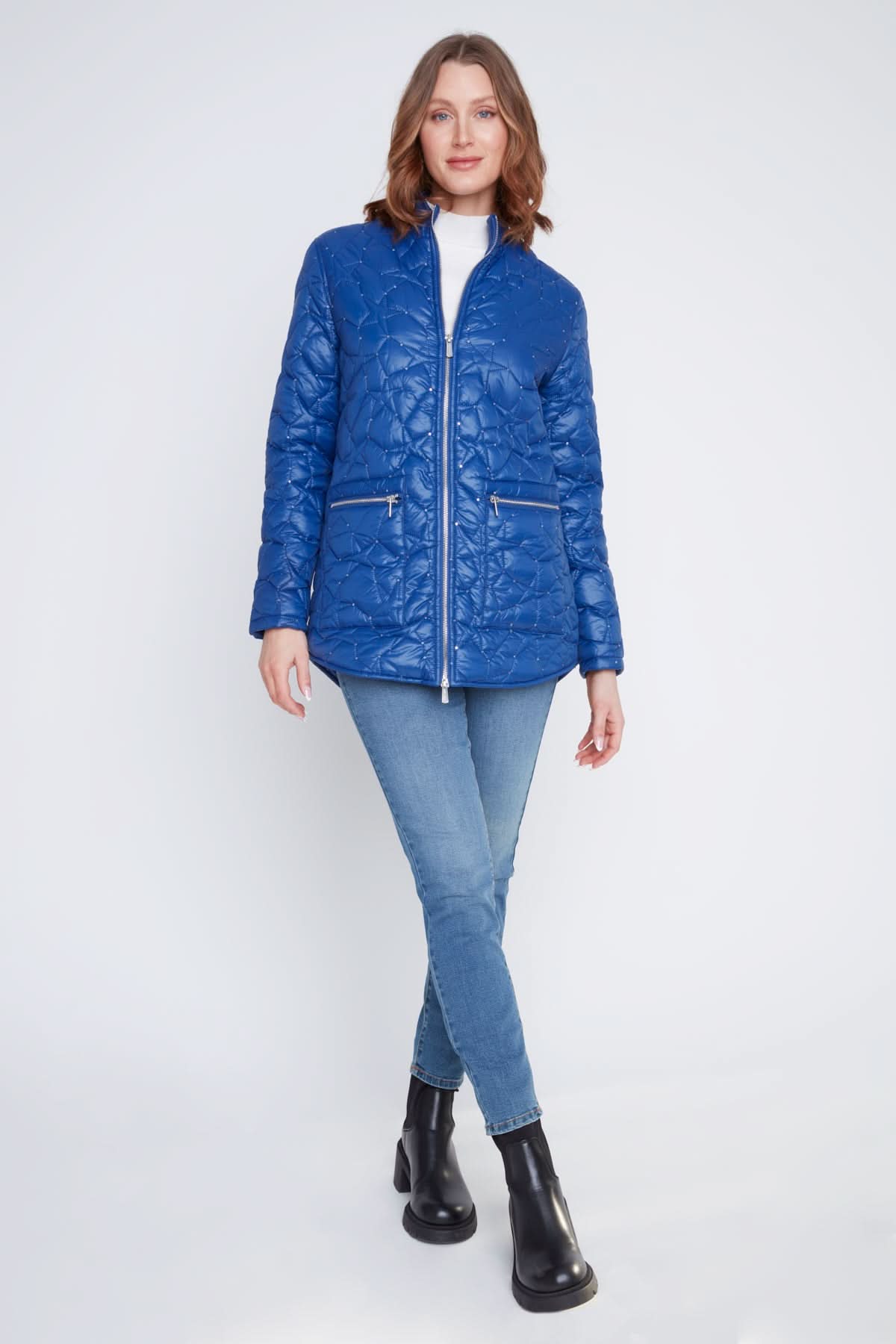 A woman stands with arms crossed, wearing the CoCo Y Club Woven Puff Jacket in blue, featuring zippered pockets, over a white top and blue jeans against a plain light background.