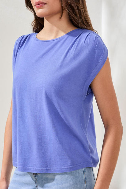 A woman wears the Tribal Boatneck cap sleeve top in purple, featuring pleated shoulders and a loose cotton blend fit, paired with light blue jeans against a neutral background.