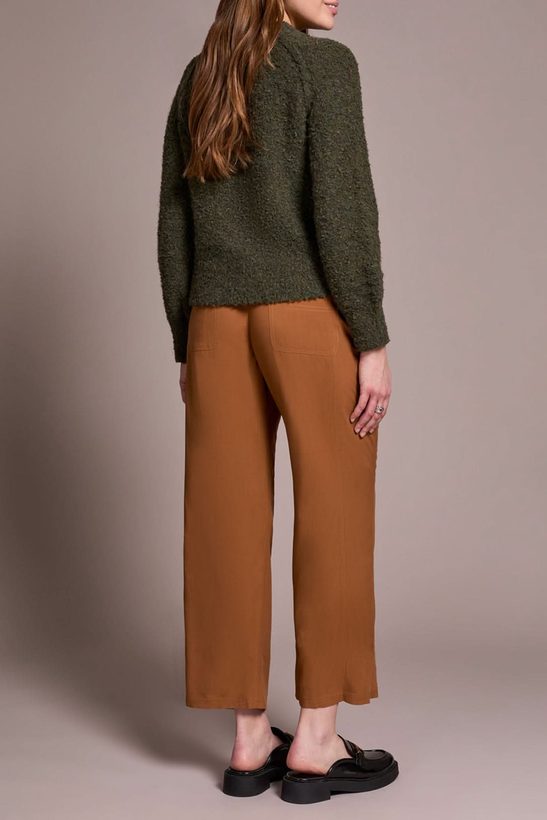 A woman wears brown pants and a Tribal Knit Crewneck Sweater Ivy.