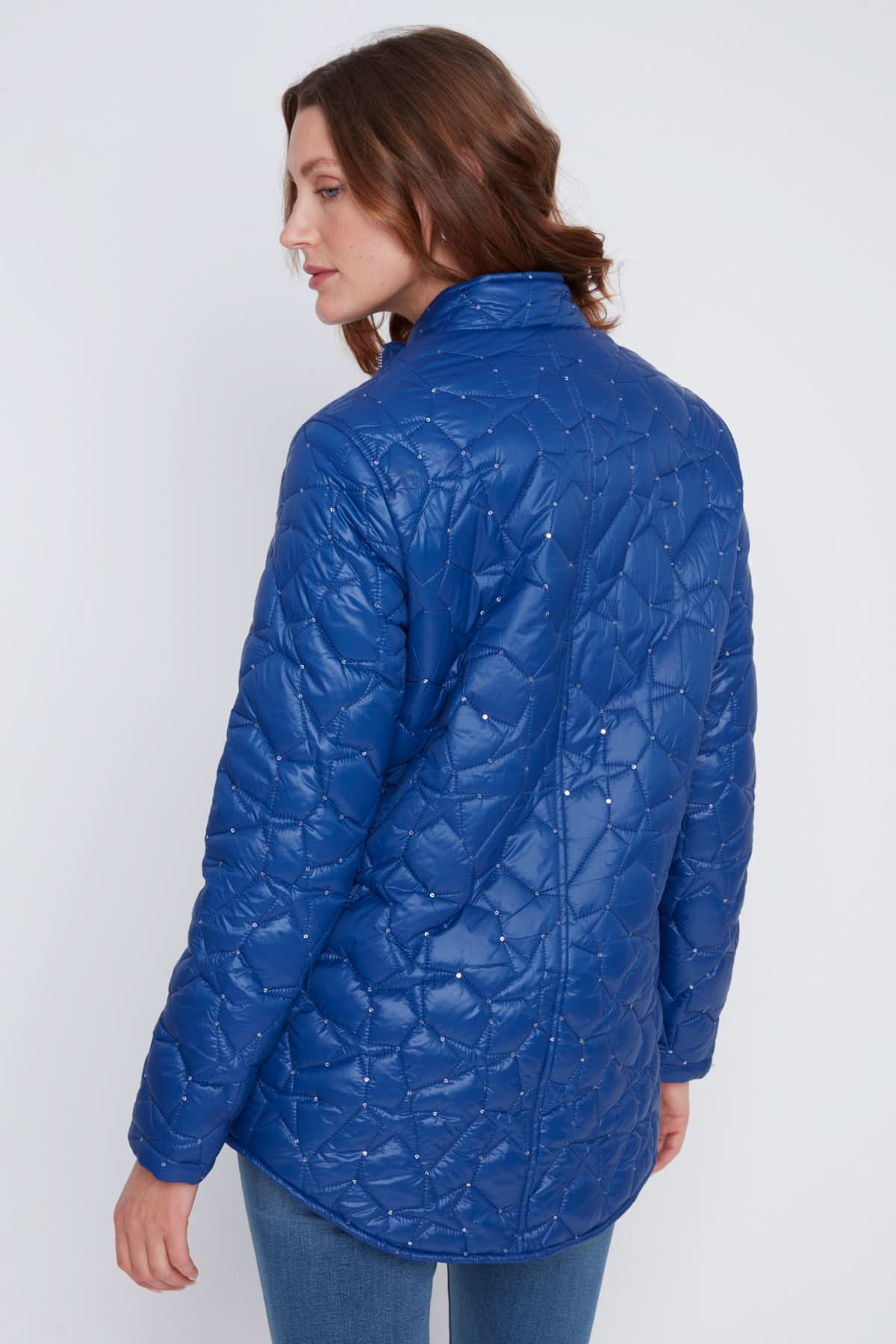A woman stands with arms crossed, wearing the CoCo Y Club Woven Puff Jacket in blue, featuring zippered pockets, over a white top and blue jeans against a plain light background.