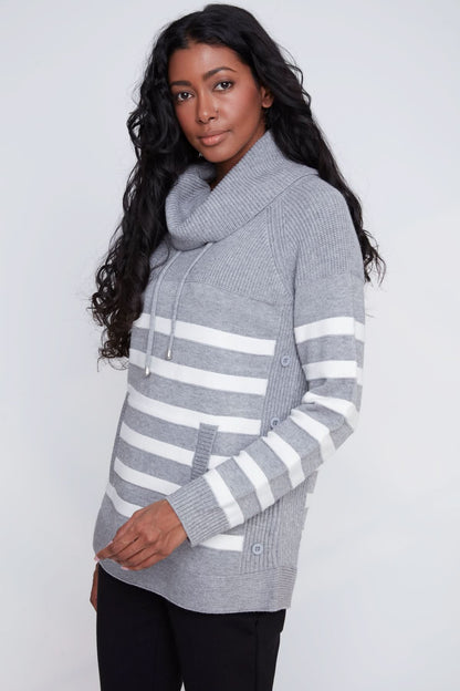 A woman models the CoCo Y Club Knitted Sweater, showcasing gray and white stripes, a cowl neck, front pockets, and side button details against a plain light background.