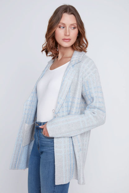 A woman stands with one hand in her pocket, wearing a cozy sweater under the CoCo Y Club Blazer Cardigan in light blue and gray plaid, paired with blue jeans and looking to the side.