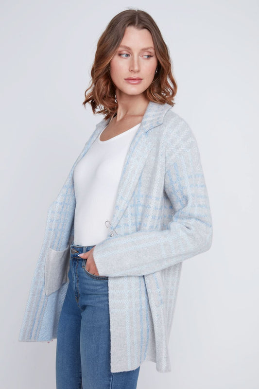 A woman stands with one hand in her pocket, wearing a cozy sweater under the CoCo Y Club Blazer Cardigan in light blue and gray plaid, paired with blue jeans and looking to the side.