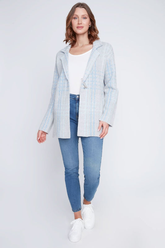 A woman stands with one hand in her pocket, wearing a cozy sweater under the CoCo Y Club Blazer Cardigan in light blue and gray plaid, paired with blue jeans and looking to the side.