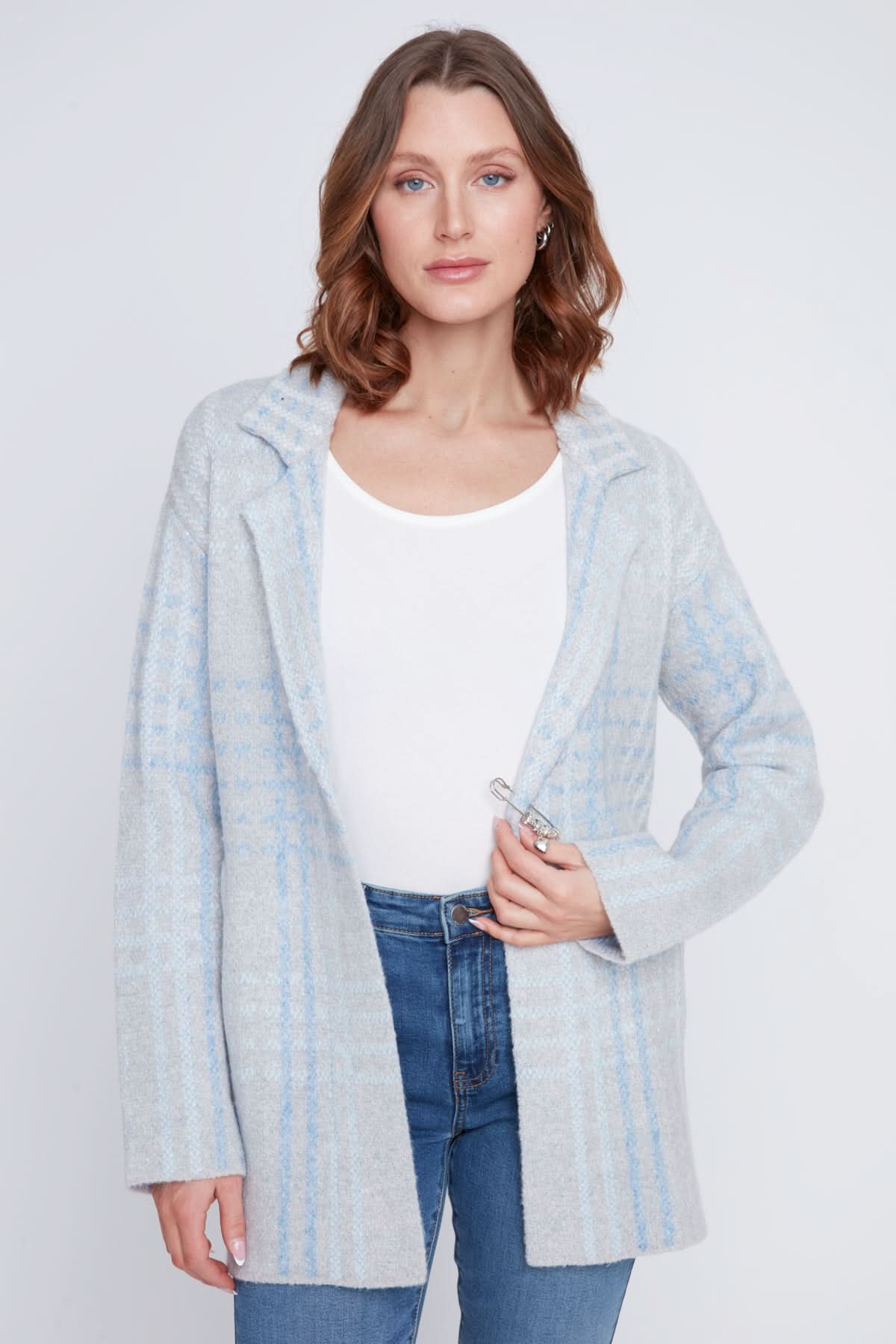 A woman stands with one hand in her pocket, wearing a cozy sweater under the CoCo Y Club Blazer Cardigan in light blue and gray plaid, paired with blue jeans and looking to the side.