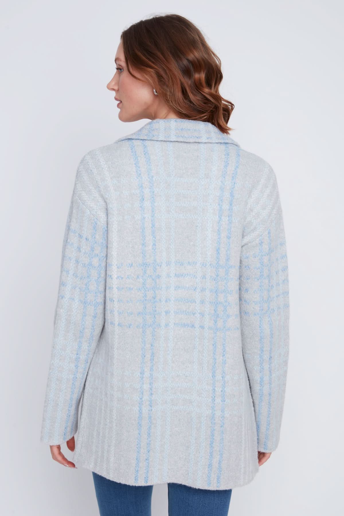 A woman stands with one hand in her pocket, wearing a cozy sweater under the CoCo Y Club Blazer Cardigan in light blue and gray plaid, paired with blue jeans and looking to the side.