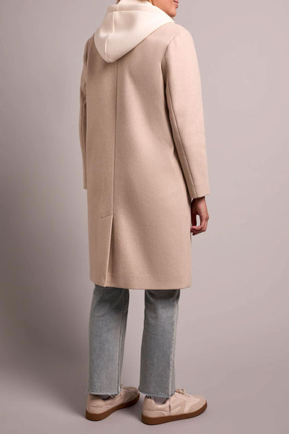 A person models the Tribal TRENCH COAT W/HOODIE, paired with light blue jeans and white sneakers, against a plain background.