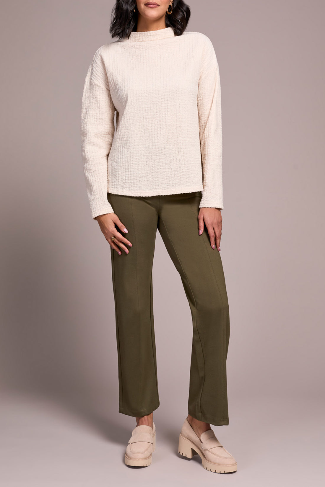 A person wears the Tribal FUNNEL NECK DOLMAN TOP in textured cream, olive green pants, and beige loafers, standing against a plain light background.