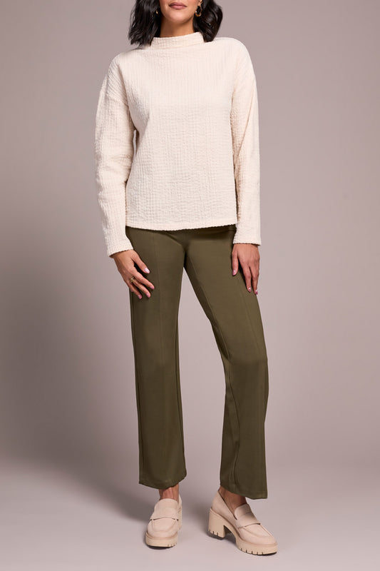 A person wears the Tribal FUNNEL NECK DOLMAN TOP in textured cream, olive green pants, and beige loafers, standing against a plain light background.