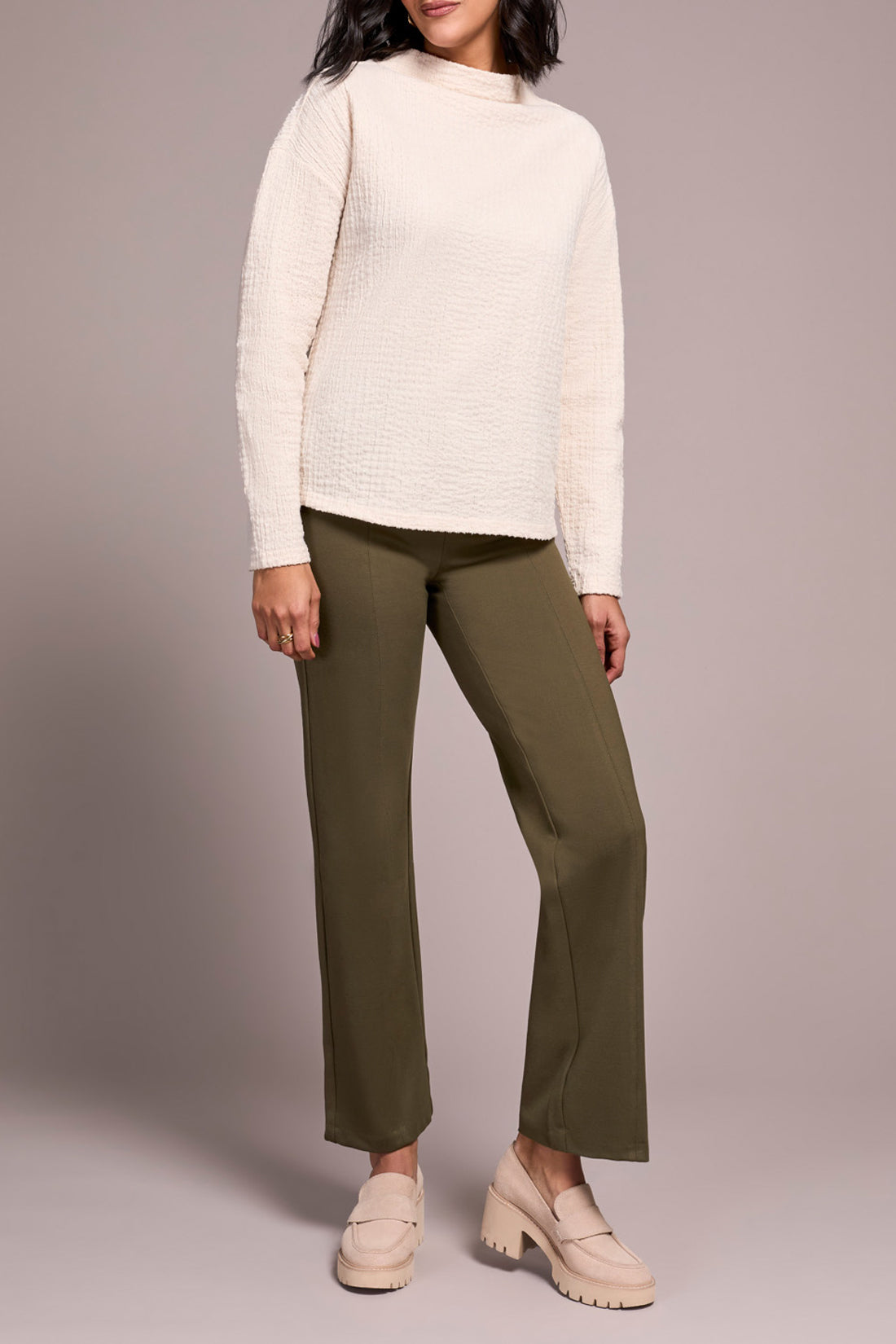 A person wears the Tribal FUNNEL NECK DOLMAN TOP in textured cream, olive green pants, and beige loafers, standing against a plain light background.