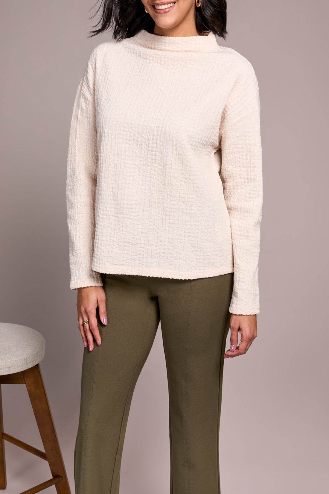 A person wears the Tribal FUNNEL NECK DOLMAN TOP in textured cream, olive green pants, and beige loafers, standing against a plain light background.