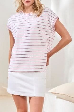 A woman wears the Tribal CAP SLEEVE TOP—white cotton-spandex with thin red stripes—paired with white bottoms. Soft, neutral lighting highlights this wardrobe basic’s versatility.