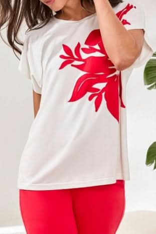 A woman wearing the Tribal CAP SLEEVE TOP in ultra-soft jersey with a large red floral patch on the front, paired with red pants.