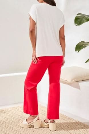 A woman wearing the Tribal CAP SLEEVE TOP in ultra-soft jersey with a large red floral patch on the front, paired with red pants.