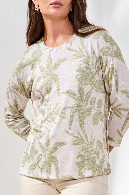 A woman models the Tribal 3/4 sleeve Crew Neck Top with a green leaf print, paired with beige pants, against a plain white background.