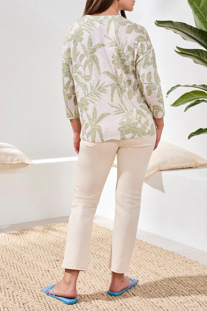 A woman models the Tribal 3/4 sleeve Crew Neck Top with a green leaf print, paired with beige pants, against a plain white background.