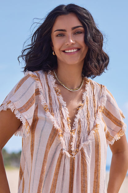 A woman with shoulder-length dark hair stands outdoors, smiling at the camera under a blue sky while wearing the Tribal Cap Sleeve T-Blouse.