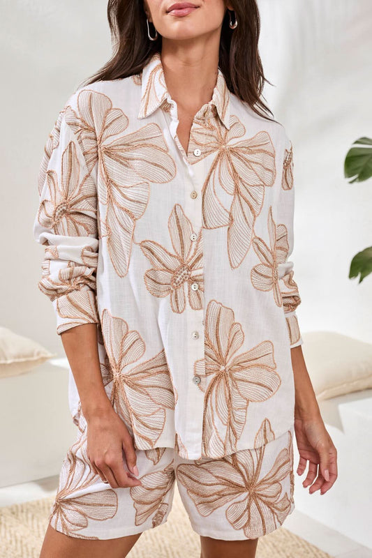 A woman stands smiling with hands in pockets, wearing the Tribal Long Sleeve Button Up Blouse and matching shorts featuring a bold tropical leaf print.