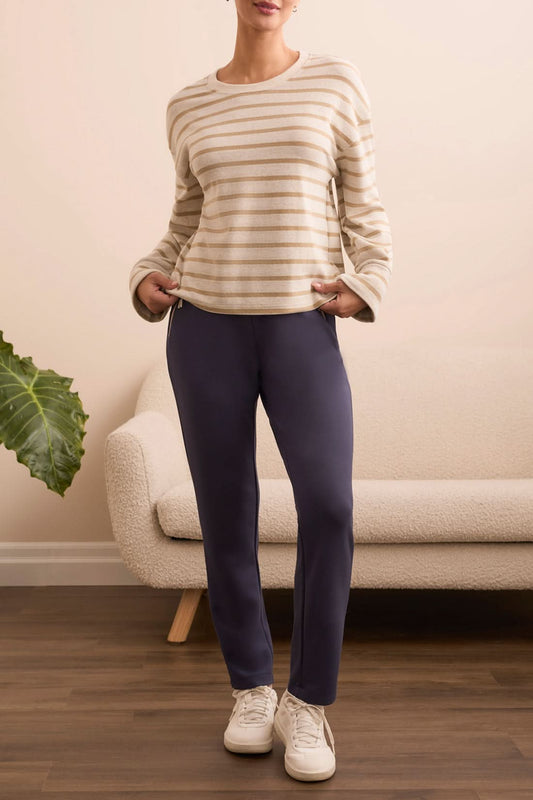 Wearing the Tribal CREW NECK TOP W/CUFF, a person stands indoors in front of a light-colored sofa, styled with navy blue pants and white sneakers.