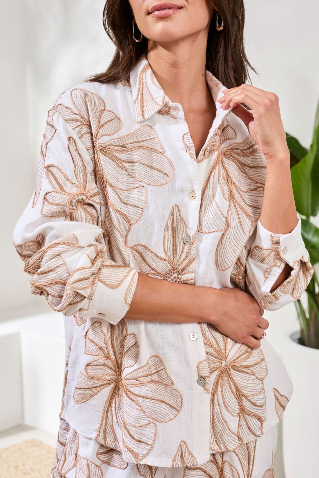 A woman stands smiling with hands in pockets, wearing the Tribal Long Sleeve Button Up Blouse and matching shorts featuring a bold tropical leaf print.