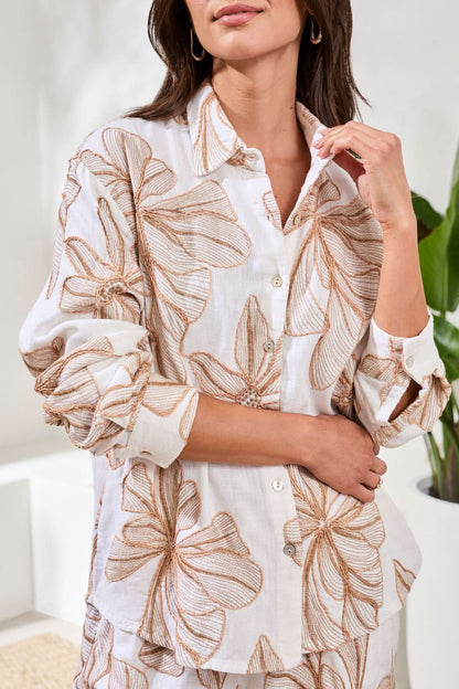 A woman stands smiling with hands in pockets, wearing the Tribal Long Sleeve Button Up Blouse and matching shorts featuring a bold tropical leaf print.