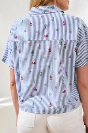 A person wears the Tribal Short Sleeve Button up with blue and white stripes and floral pattern, paired with white frayed hem shorts and brown sandals indoors—a perfect casual day wardrobe staple.