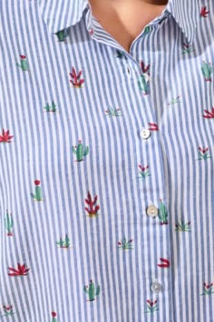 A person wears the Tribal Short Sleeve Button up with blue and white stripes and floral pattern, paired with white frayed hem shorts and brown sandals indoors—a perfect casual day wardrobe staple.