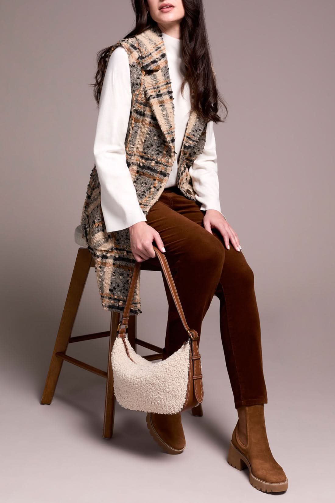 A woman models the Tribal WIDE NOTCH COLLAR VEST—a plaid, sleeveless coat with a wide notch collar—layered over a white turtleneck, rust pants, and brown boots while holding a handbag against a plain background.