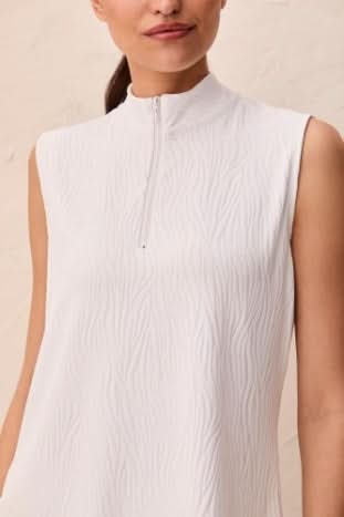 A woman models the Tribal TEXTURED QUARTER ZIP, a sleeveless white top with a high mock neck and quarter zip, shown from shoulders to mid-torso.