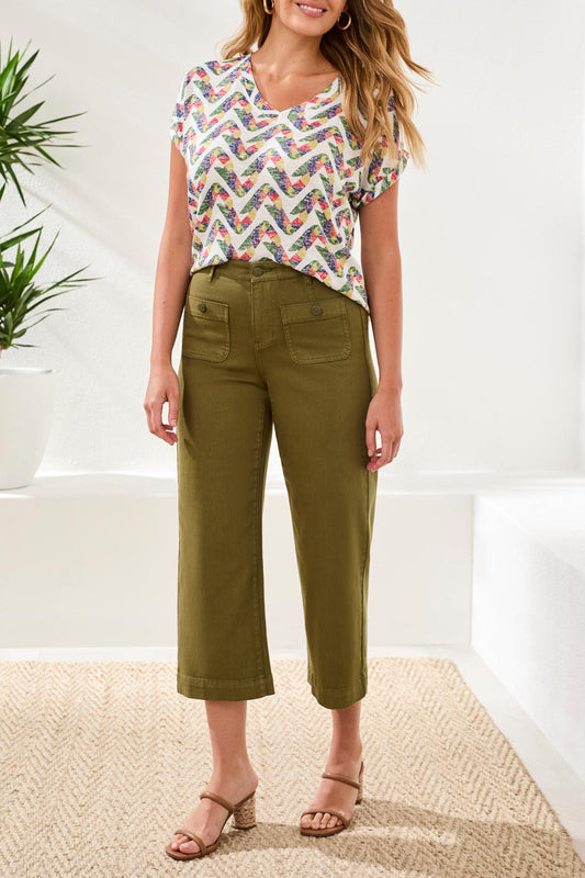 A woman stands indoors wearing a patterned short-sleeve top, Tribal Sophia Crop Palazzo Pant with a flattering fit and front pockets, paired with beige heeled sandals.