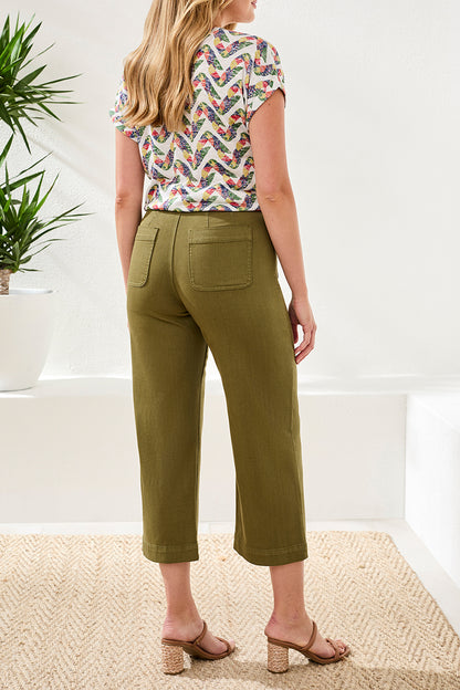 A woman stands indoors wearing a patterned short-sleeve top, Tribal Sophia Crop Palazzo Pant with a flattering fit and front pockets, paired with beige heeled sandals.