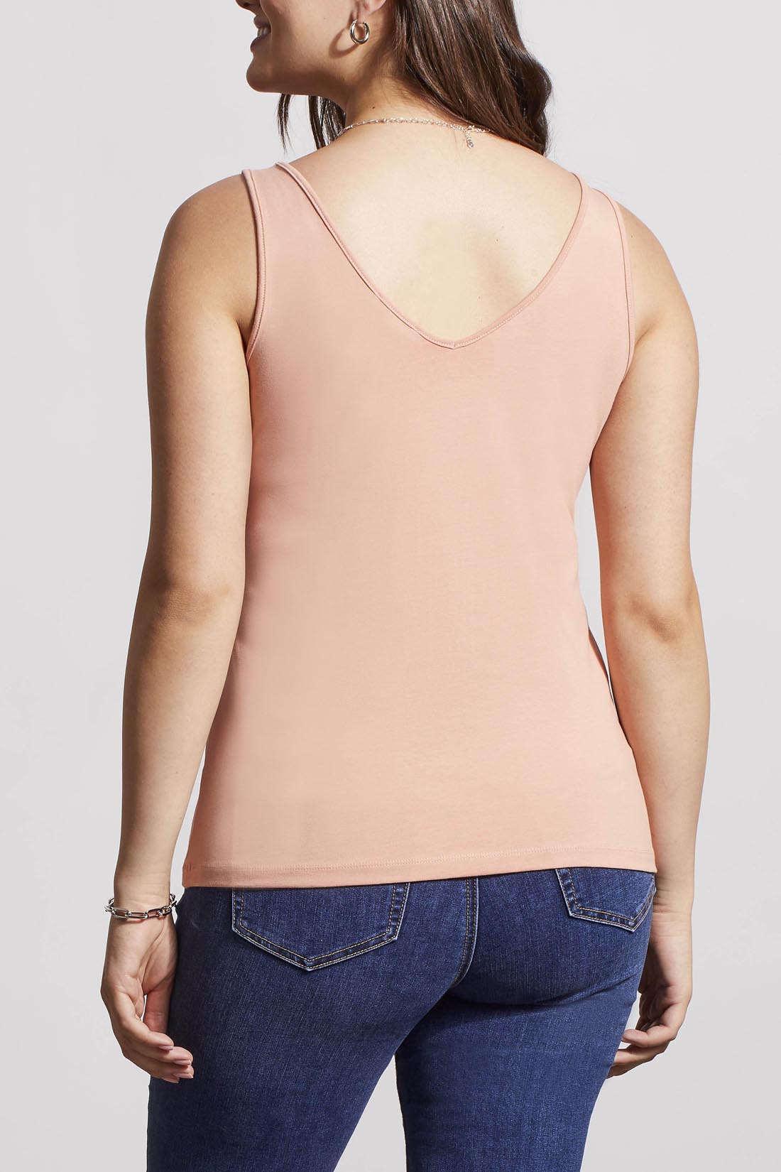 A woman in a cream Tribal Two Way Camisole and blue jeans, standing with one hand partially in her pocket.